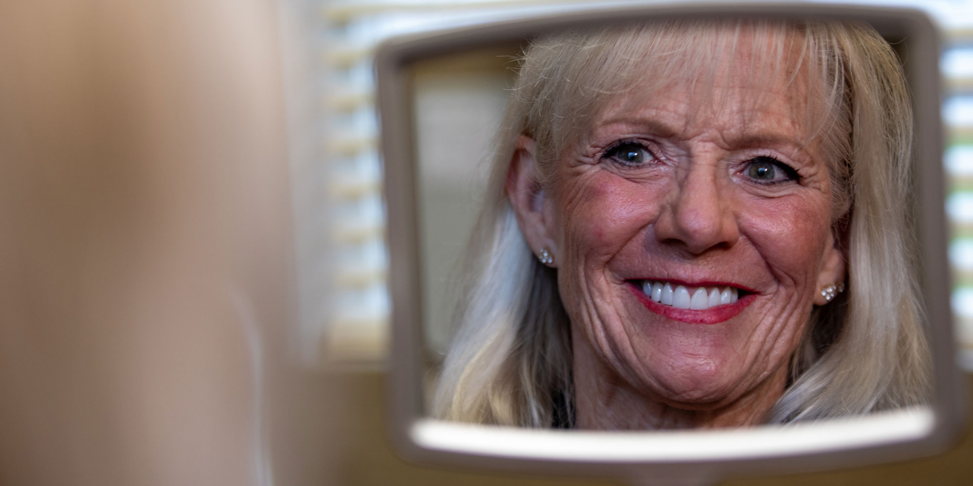 woman smiling into mirror