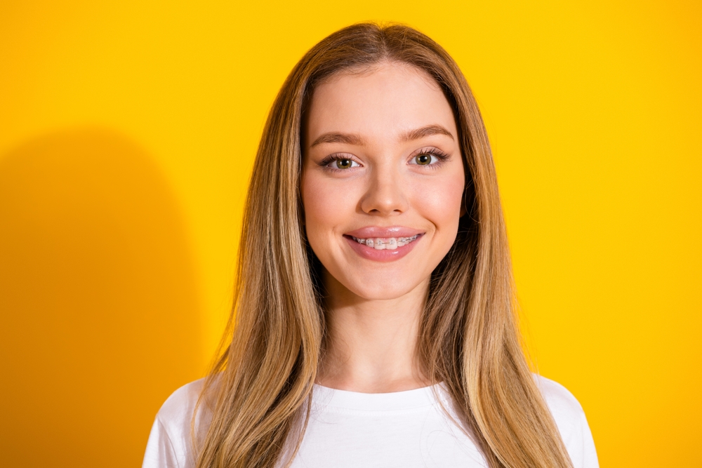 young girl smiling, background is yellow